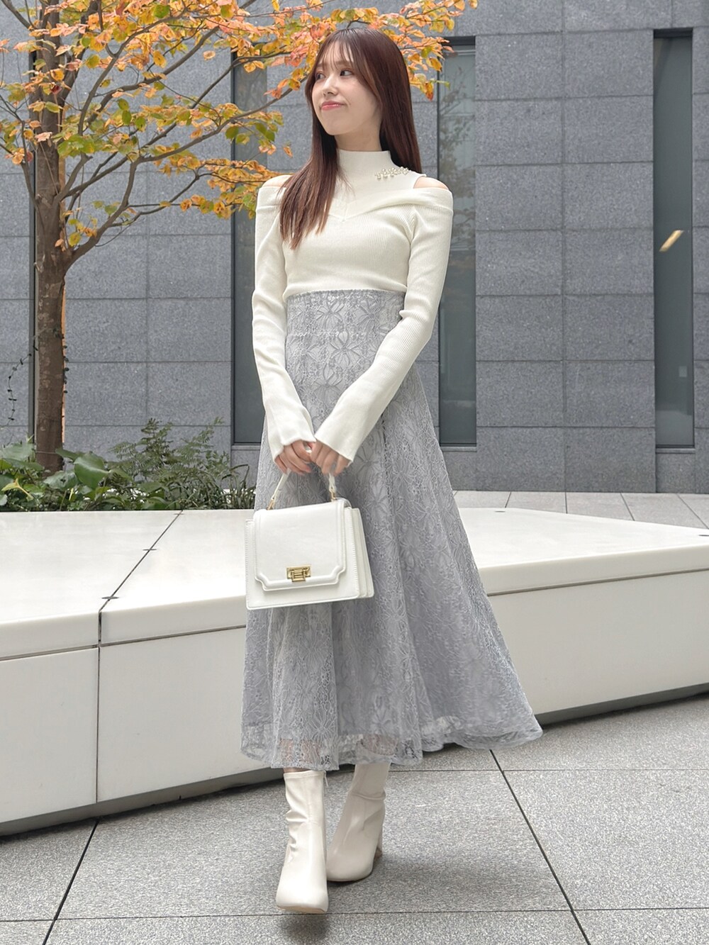 ホワイト系のハンドバッグ、ホワイト系のブーツ、ホワイト系のニット/セーターを着用したレディースの冬コーディネートの2枚目の写真