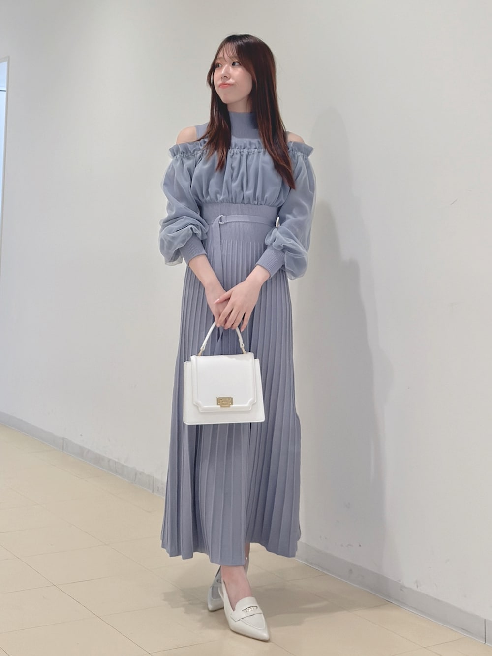 ブルー系のワンピース、ホワイト系のハンドバッグ、ホワイト系のパンプスを着用したレディースの冬コーディネートの2枚目の写真