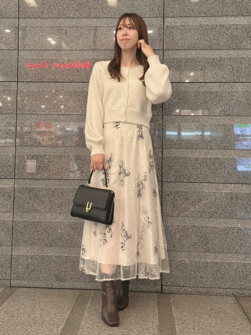 ホワイト系のカーディガン/ボレロ、ホワイト系のスカート、ブラック系のハンドバッグを着用したレディースの秋コーディネートの2枚目の写真