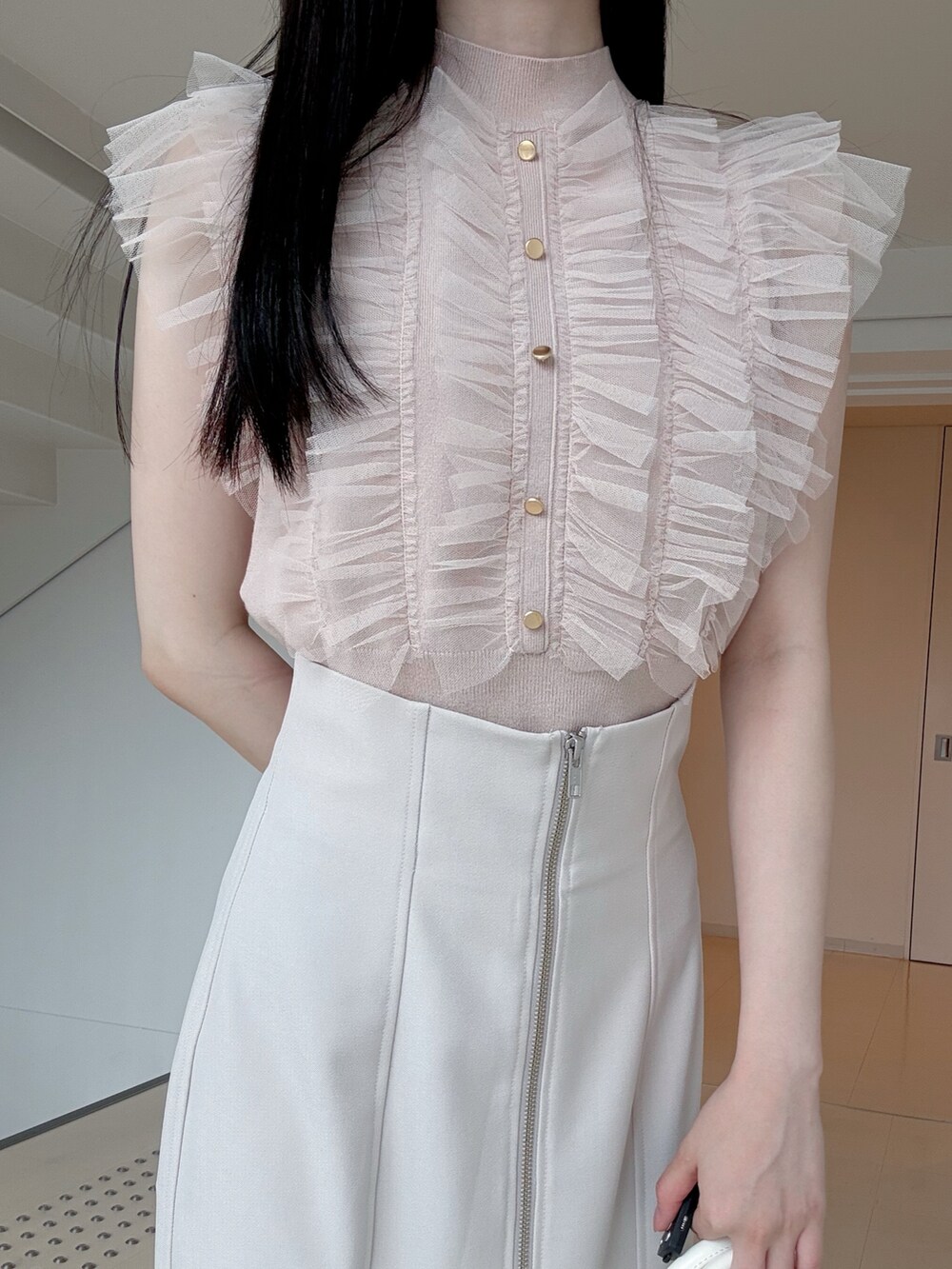 ピンク系のニット/セーター、グレー系のスカート、ホワイト系のハンドバッグを着用したレディースの夏コーディネートの5枚目の写真