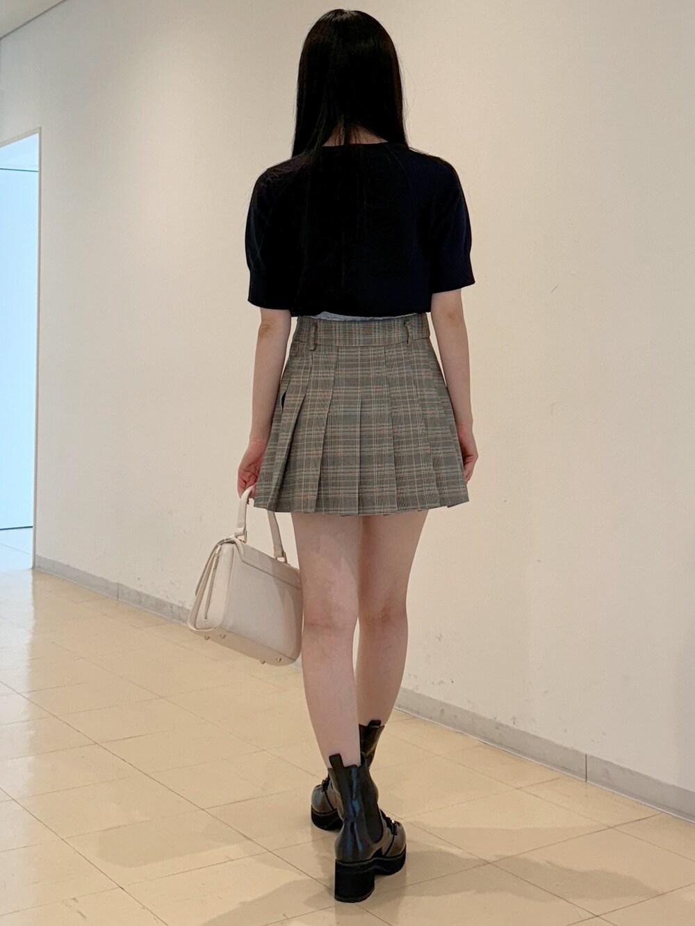 ブルー系のニット/セーター、グレー系のスカート、ホワイト系のハンドバッグを着用したレディースの夏コーディネートの5枚目の写真