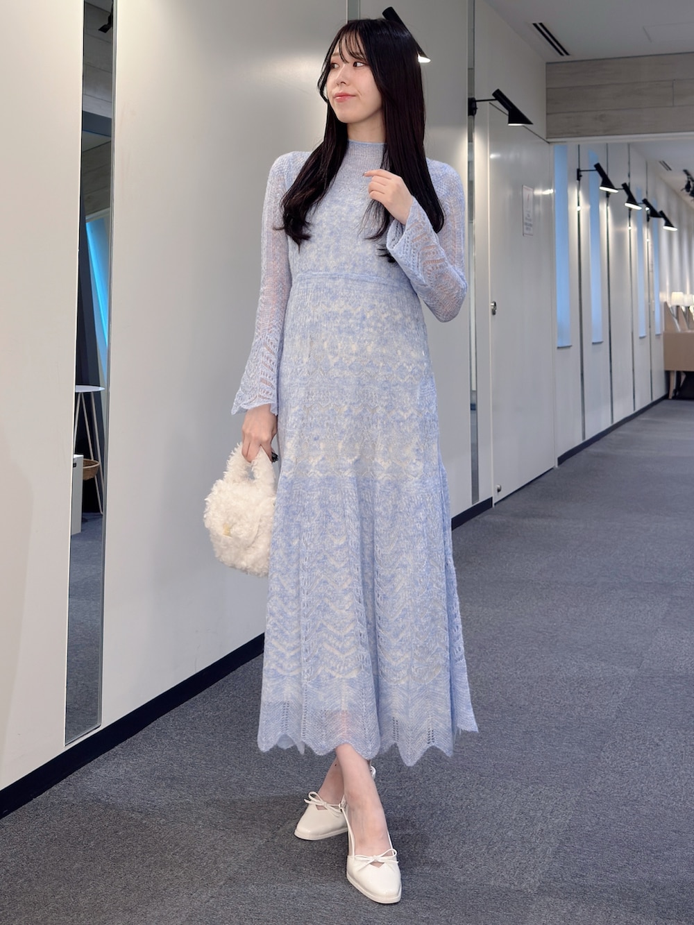 ブルー系のワンピース、ホワイト系のハンドバッグ、ホワイト系のパンプスを着用したレディースの秋コーディネートの2枚目の写真