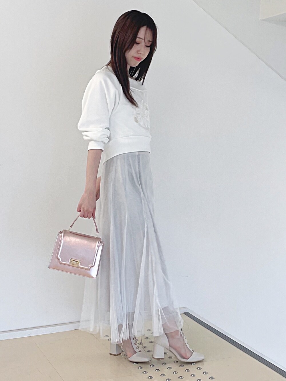 ホワイト系のスウェット、ホワイト系のスカート、ピンク系のハンドバッグを着用したレディースの秋コーディネートの4枚目の写真