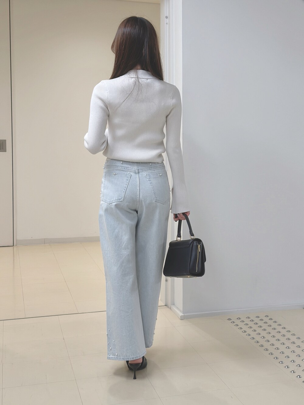 ホワイト系のカーディガン/ボレロ、ブルー系のデニムパンツ、ブラック系のハンドバッグを着用したレディースの冬コーディネートの4枚目の写真