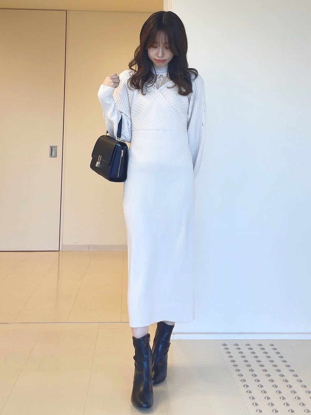 ホワイト系のワンピース、ブラック系のブーツ、ブラック系のショルダーバッグを着用したレディースの秋コーディネートの4枚目の写真