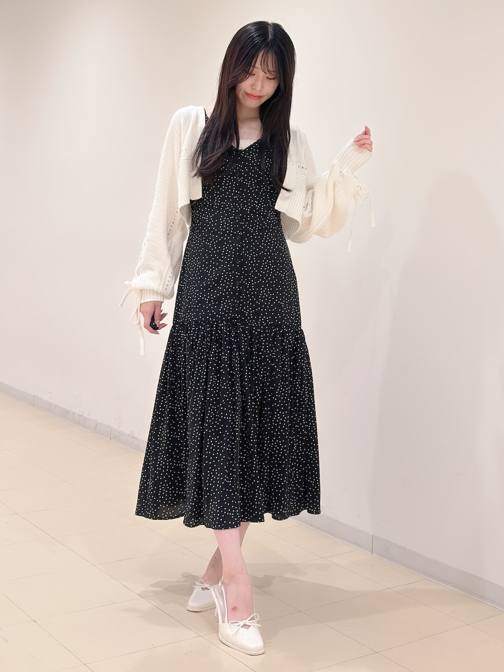 ブラック系のワンピース、ホワイト系のカーディガン/ボレロ、ホワイト系のパンプスを着用したレディースの秋コーディネートの2枚目の写真