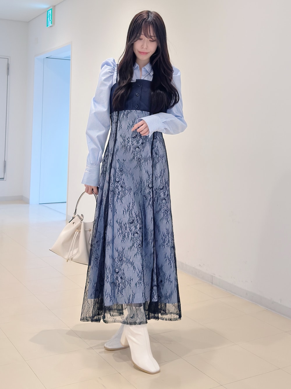 ブルー系のワンピース、ホワイト系のショルダーバッグ、ホワイト系のブーツを着用したレディースの冬コーディネートの2枚目の写真