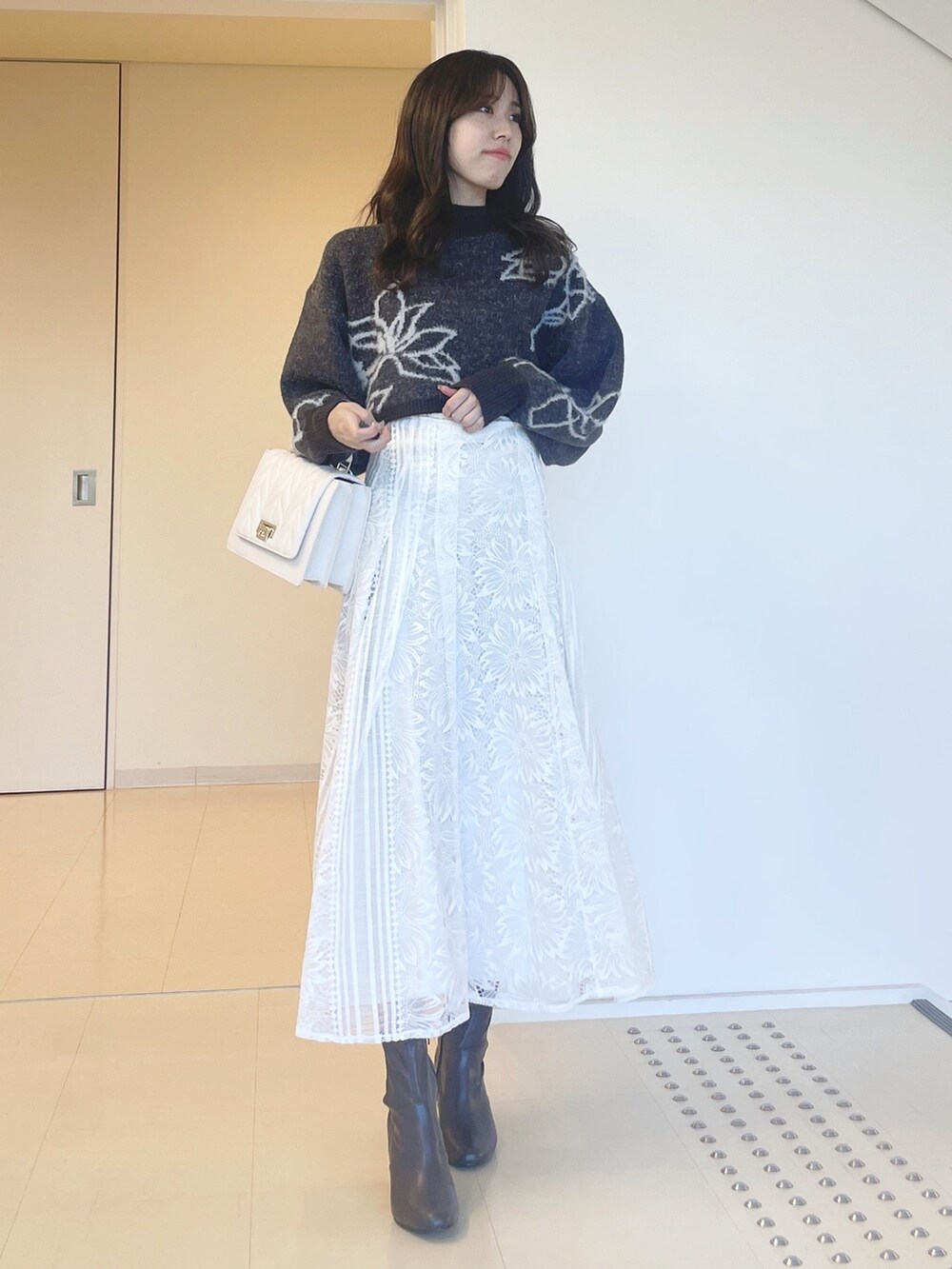 グレー系のニット/セーター、ホワイト系のスカート、ホワイト系のショルダーバッグを着用したレディースの秋コーディネートの2枚目の写真