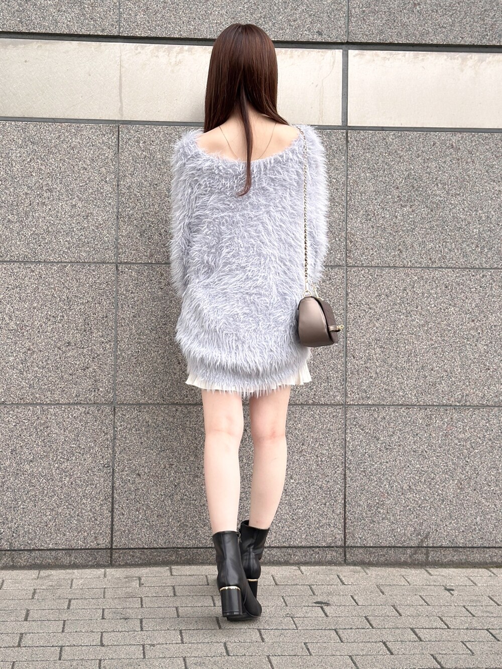 グレー系のニット/セーター、ホワイト系のスカート、ブラック系のブーツを着用したレディースの秋コーディネートの6枚目の写真