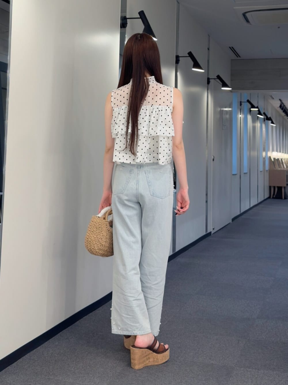 ベージュ系のハンドバッグ、ブラウン系のサンダル、ブルー系のデニムパンツを着用したレディースの夏コーディネートの4枚目の写真