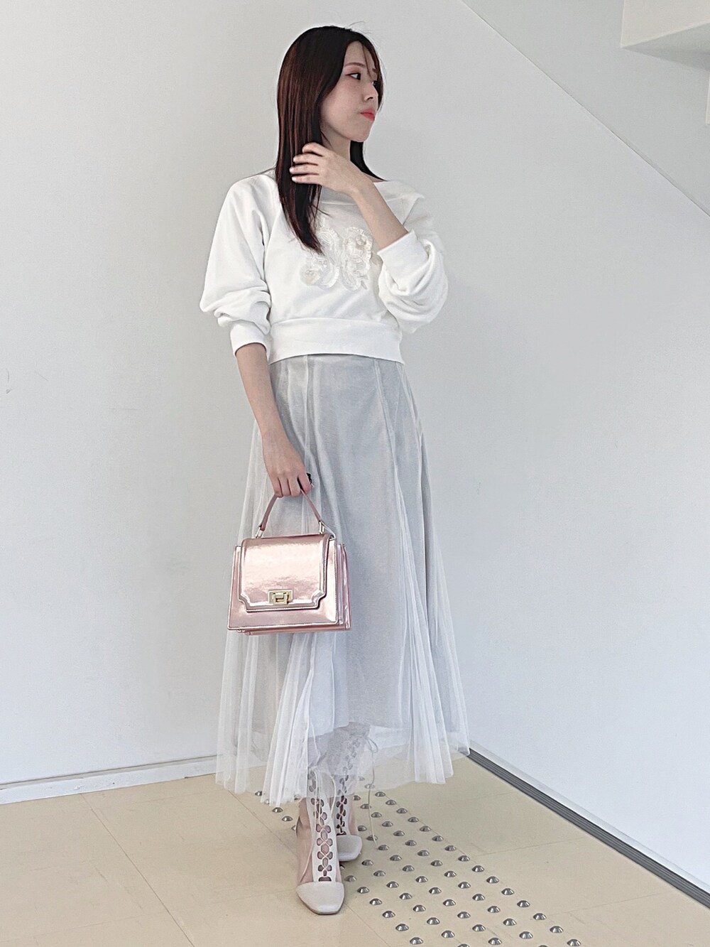 ホワイト系のスウェット、ホワイト系のスカート、ピンク系のハンドバッグを着用したレディースの秋コーディネートの3枚目の写真