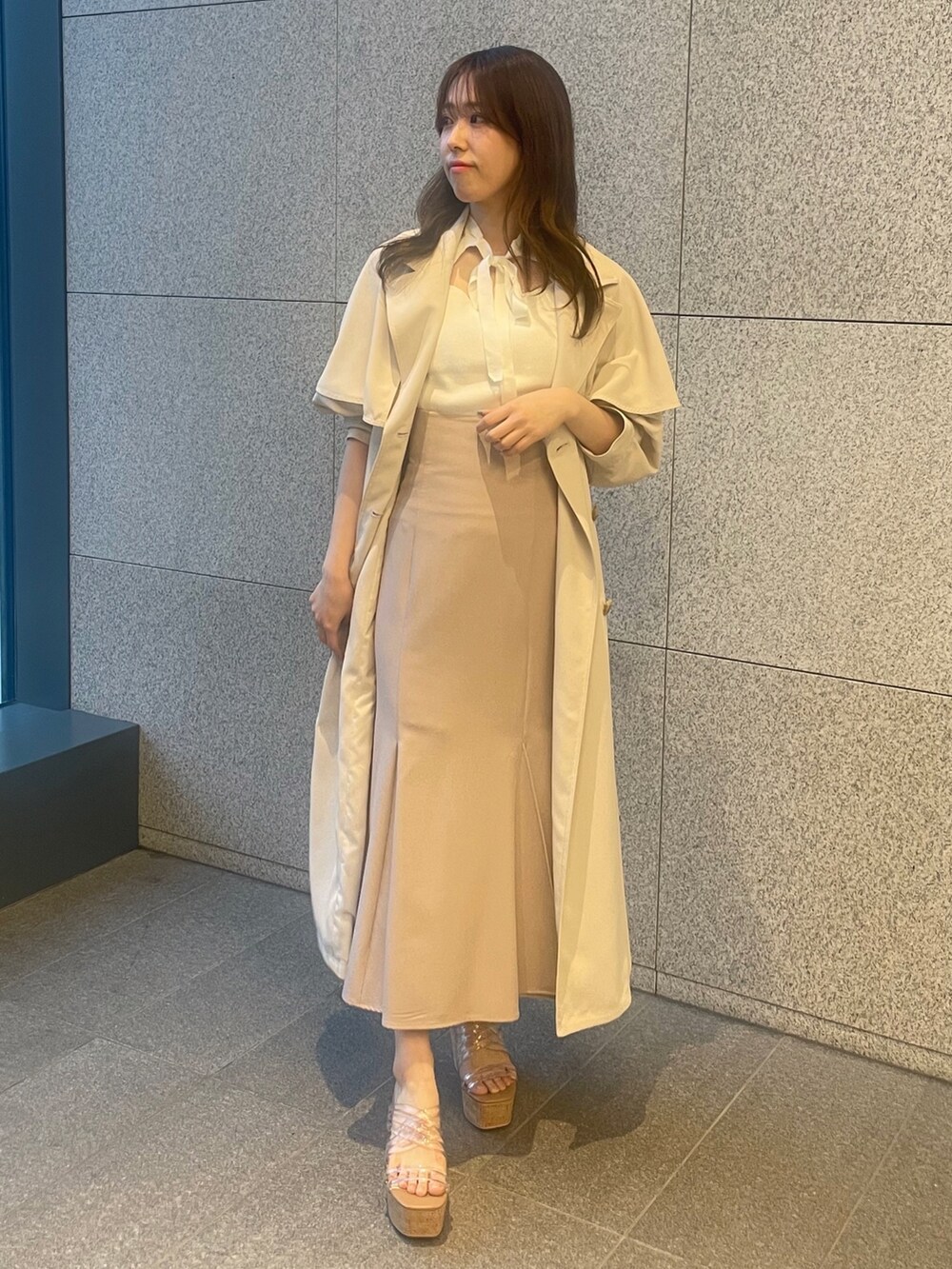 ピンク系のスカート、ホワイト系のニット/セーター、ホワイト系のトレンチコートを着用したレディースの春コーディネートの2枚目の写真