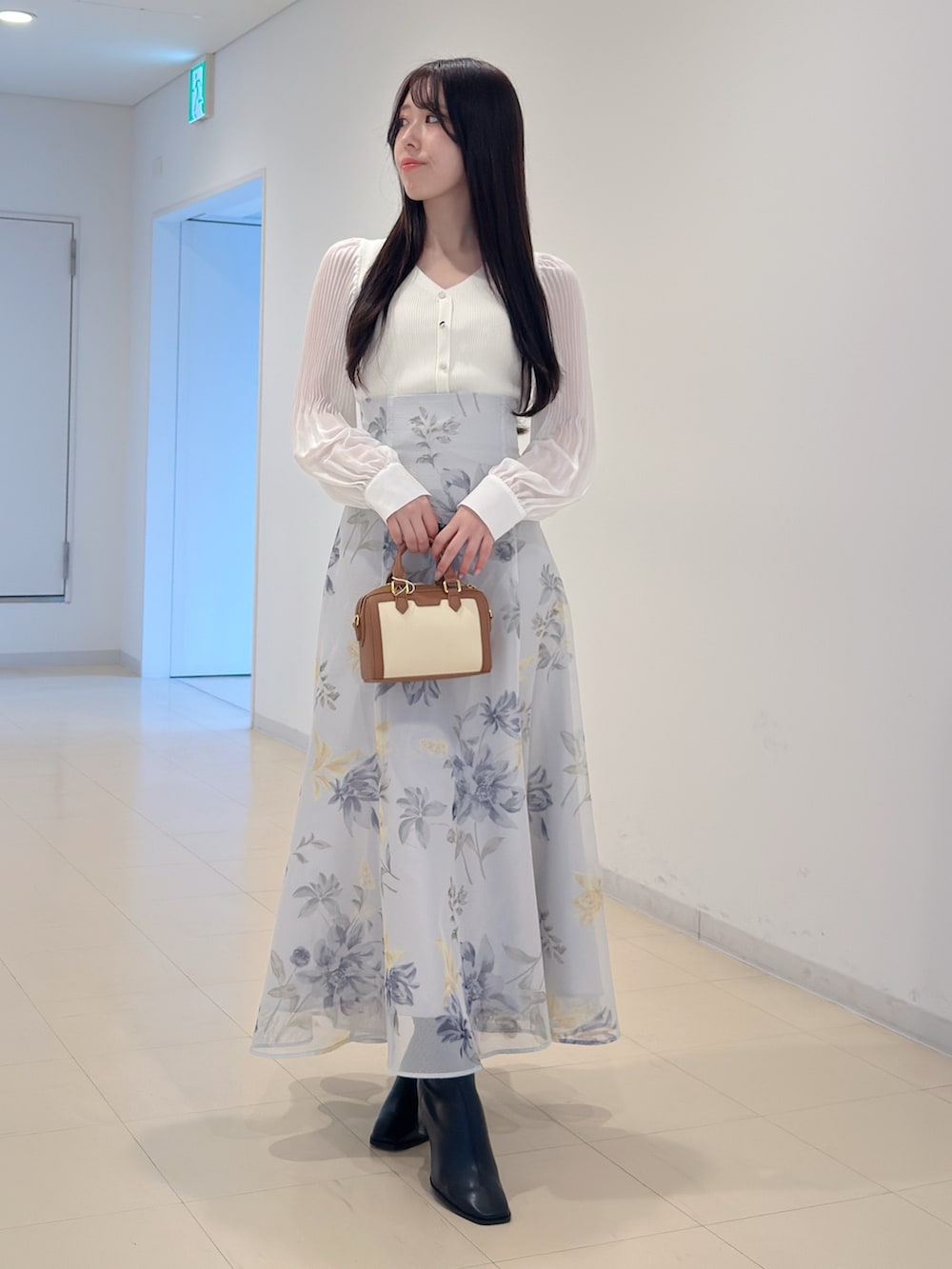 ホワイト系のニット/セーター、グリーン系のスカート、ブラウン系のハンドバッグを着用したレディースの冬コーディネートの5枚目の写真