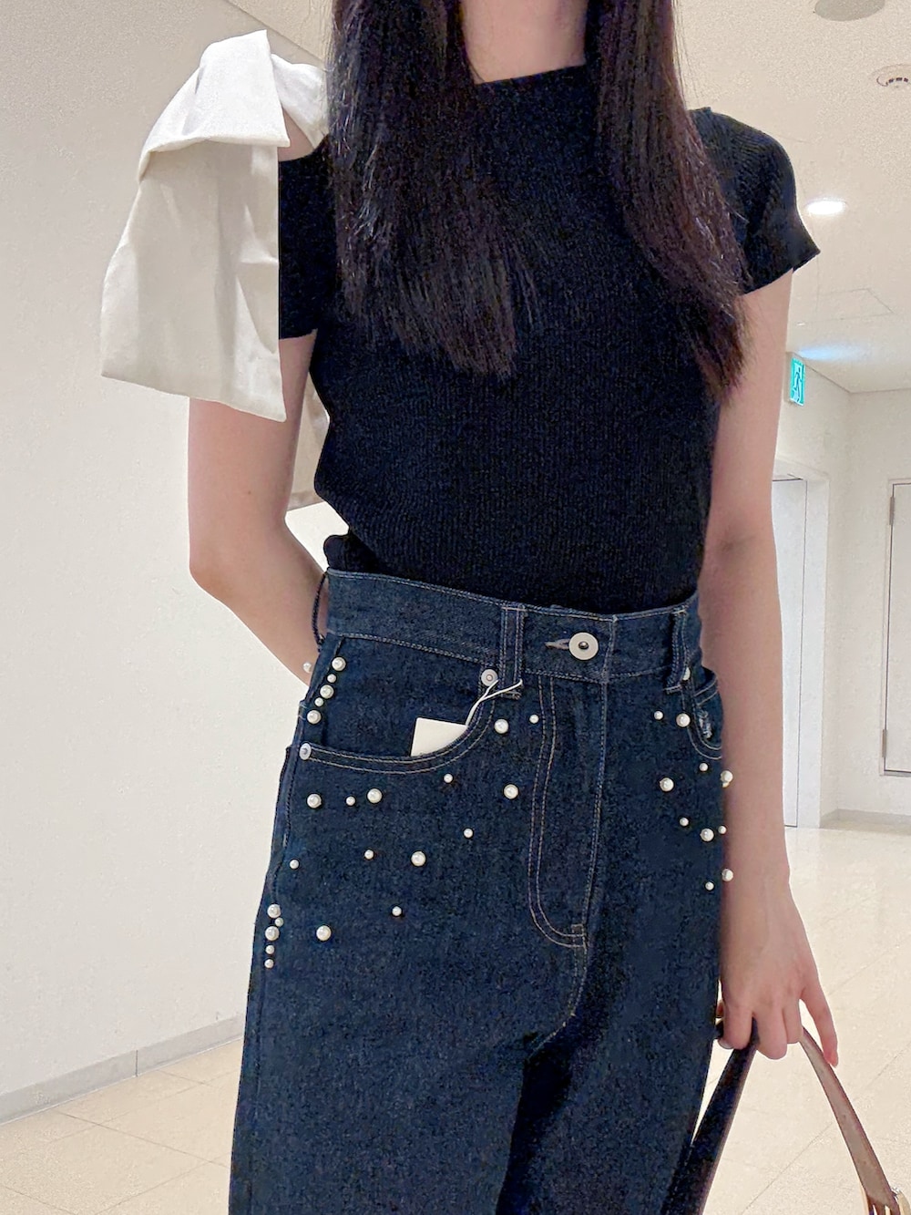 ブラック系のニット/セーター、ブルー系のデニムパンツ、ブルー系のショルダーバッグを着用したレディースの夏コーディネートの6枚目の写真