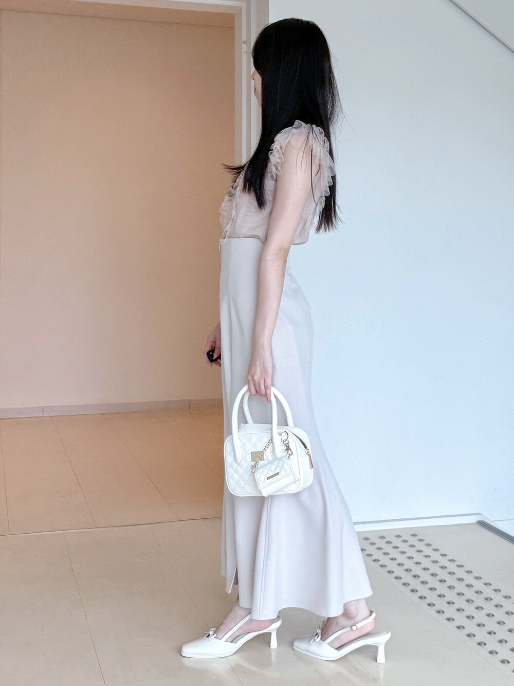 ピンク系のニット/セーター、グレー系のスカート、ホワイト系のハンドバッグを着用したレディースの夏コーディネートの3枚目の写真