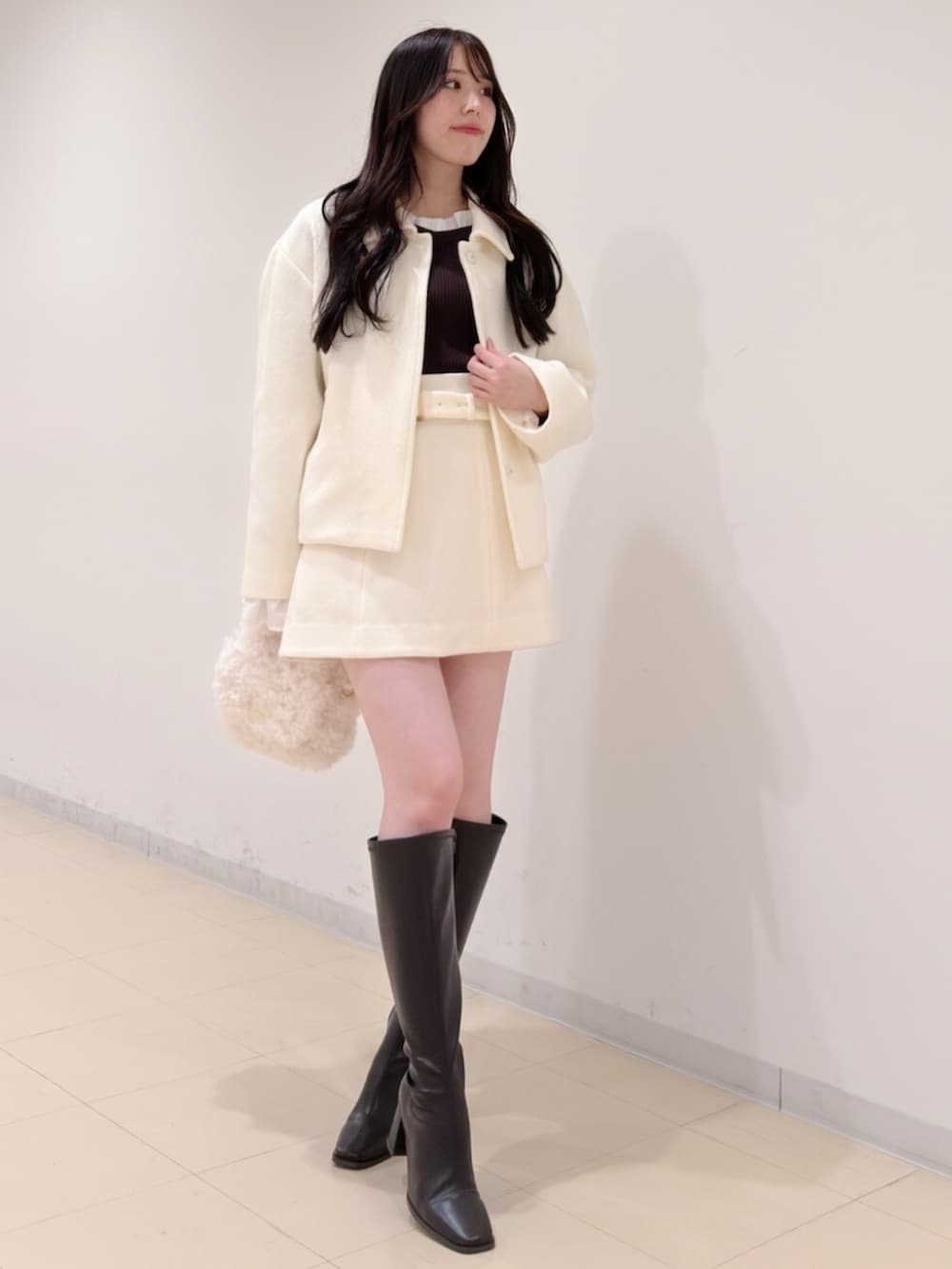 ホワイト系のハンドバッグ、ブラウン系のブーツ、ブラウン系のニット/セーターを着用したレディースの冬コーディネートの2枚目の写真