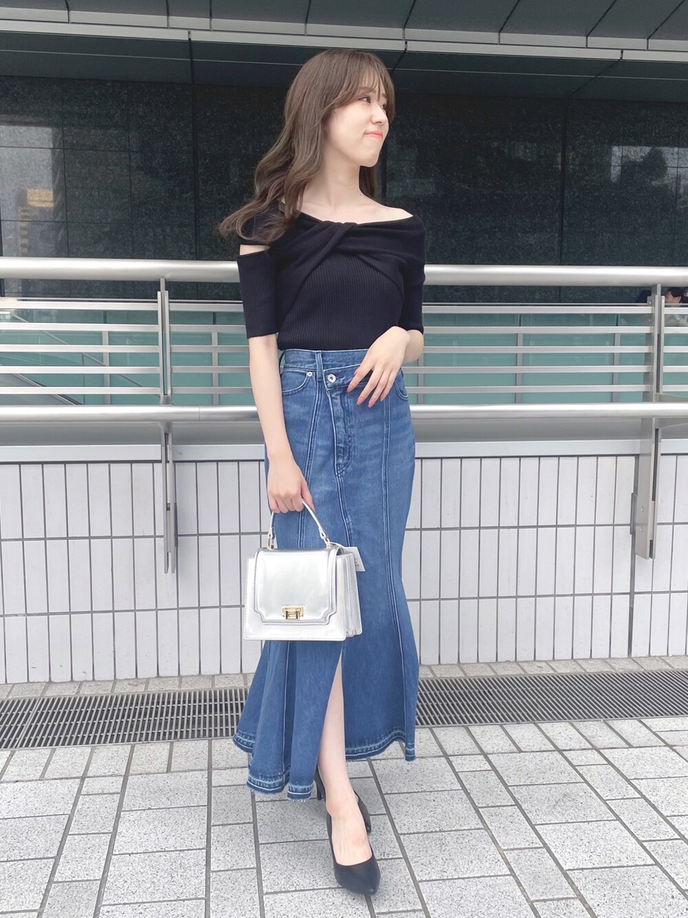 ブラック系のニット/セーター、ブルー系のデニムスカート、シルバー系のハンドバッグを着用したレディースの夏コーディネートの2枚目の写真