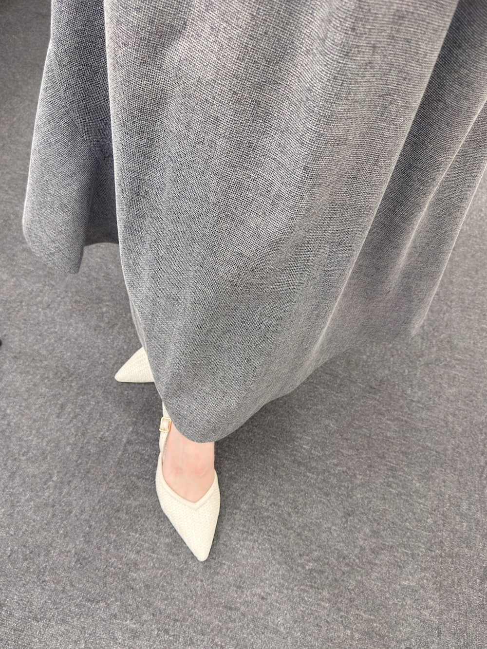 ブラック系のワンピース、ブラック系のハンドバッグ、ホワイト系のパンプスを着用したレディースの春コーディネートの6枚目の写真