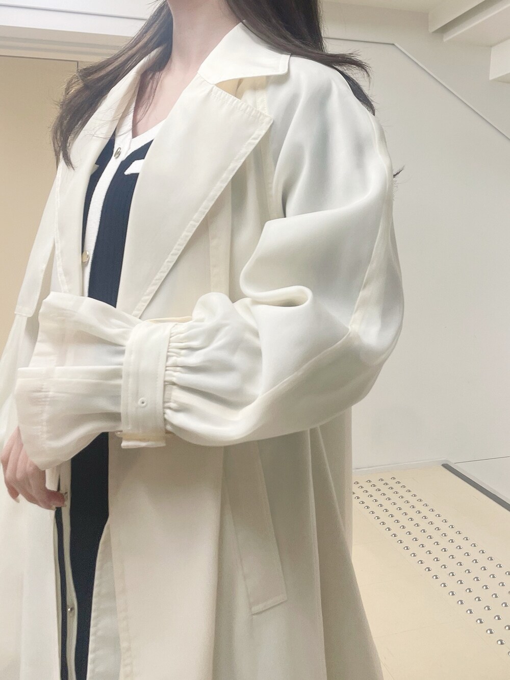 ホワイト系のトレンチコート、ブラック系のワンピース、ブラウン系のブーツを着用したレディースの冬コーディネートの5枚目の写真