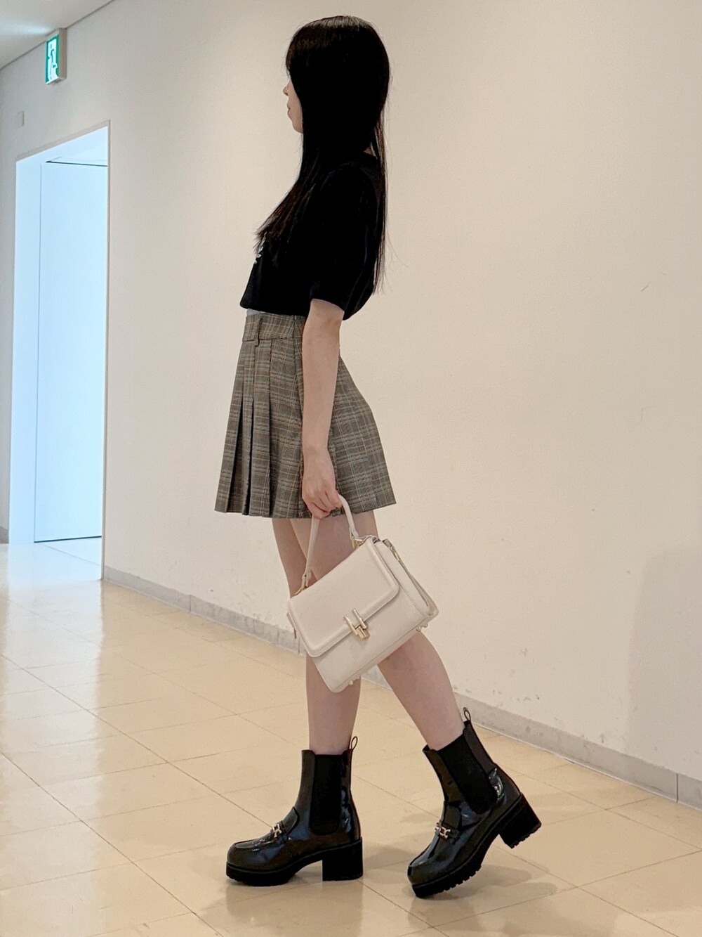 ブルー系のニット/セーター、グレー系のスカート、ホワイト系のハンドバッグを着用したレディースの夏コーディネートの4枚目の写真