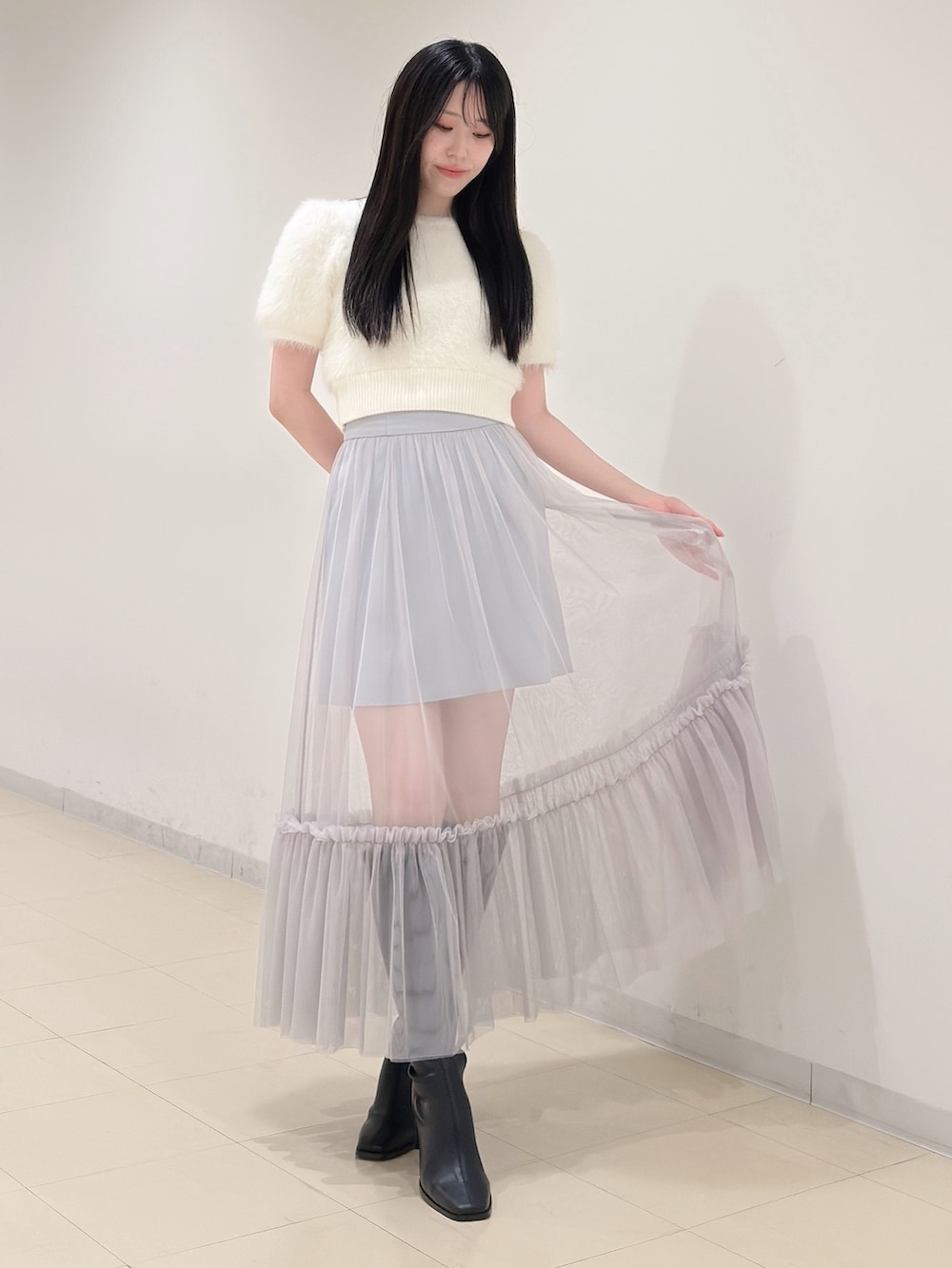 ホワイト系のニット/セーター、ブルー系のスカート、ブラック系のブーツを着用したレディースの夏コーディネートの2枚目の写真