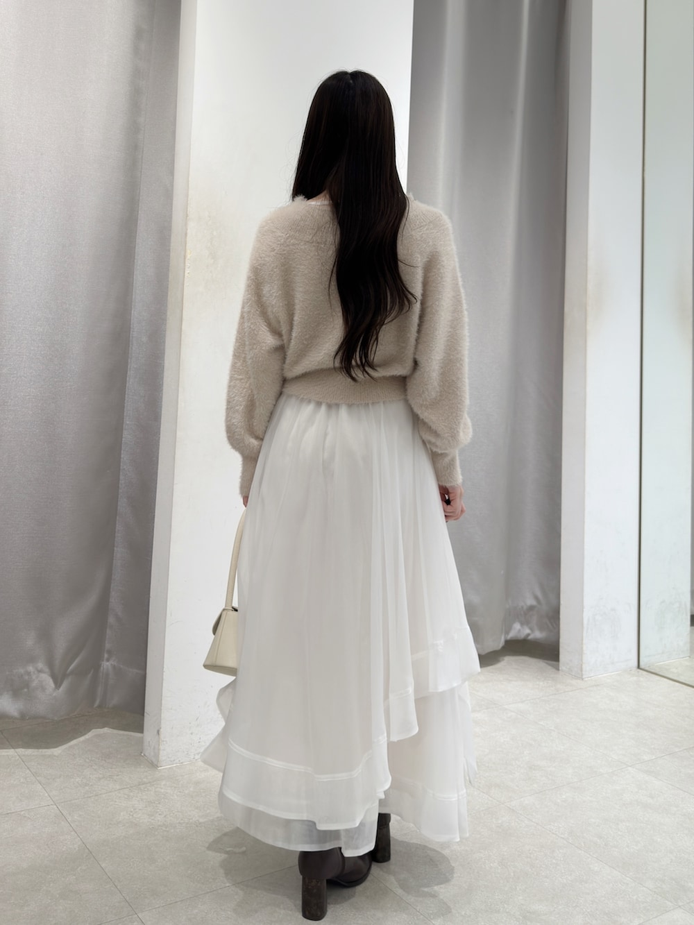 ピンク系のニット/セーター、ホワイト系のスカート、ホワイト系のハンドバッグを着用したレディースの秋コーディネートの4枚目の写真