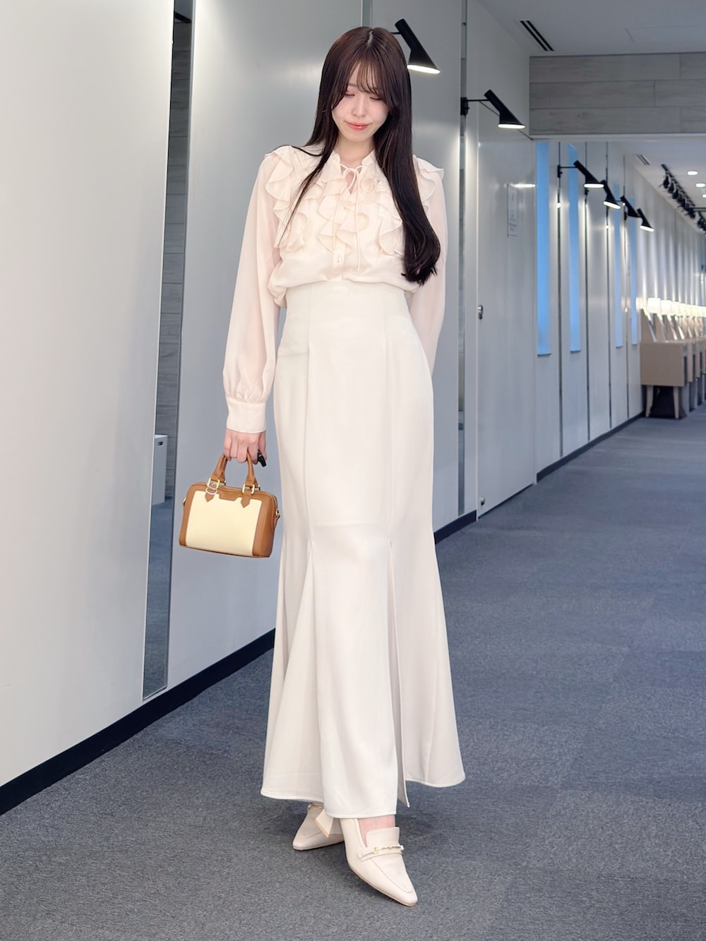 ピンク系のシャツ/ブラウス、ホワイト系のスカート、ブラウン系のハンドバッグを着用したレディースの春コーディネートの2枚目の写真