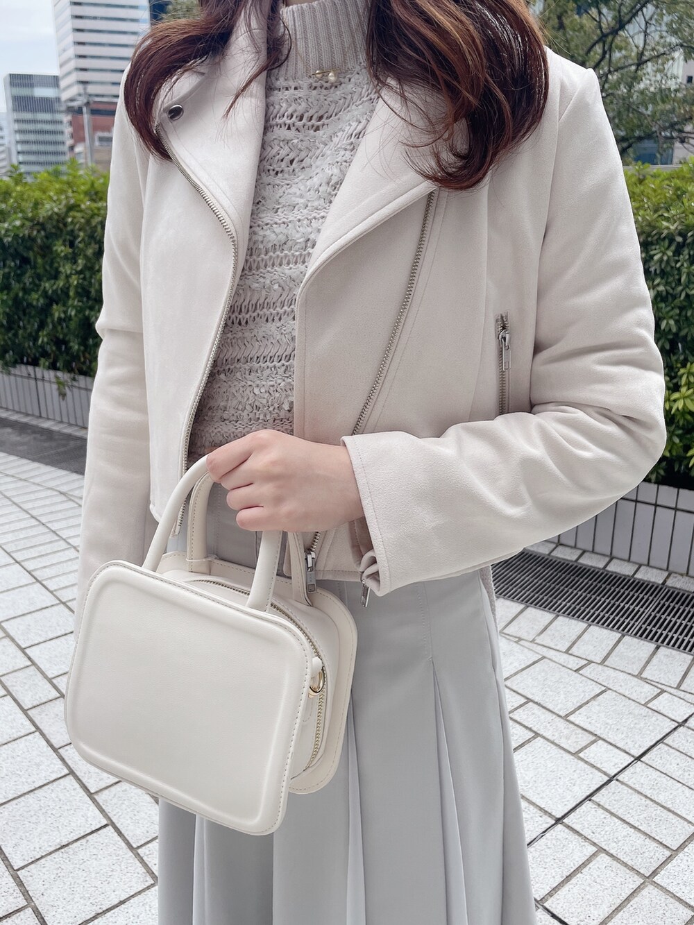 ピンク系のライダースジャケット、グレー系のニット/セーター、グリーン系のスカートを着用したレディースの冬コーディネートの4枚目の写真