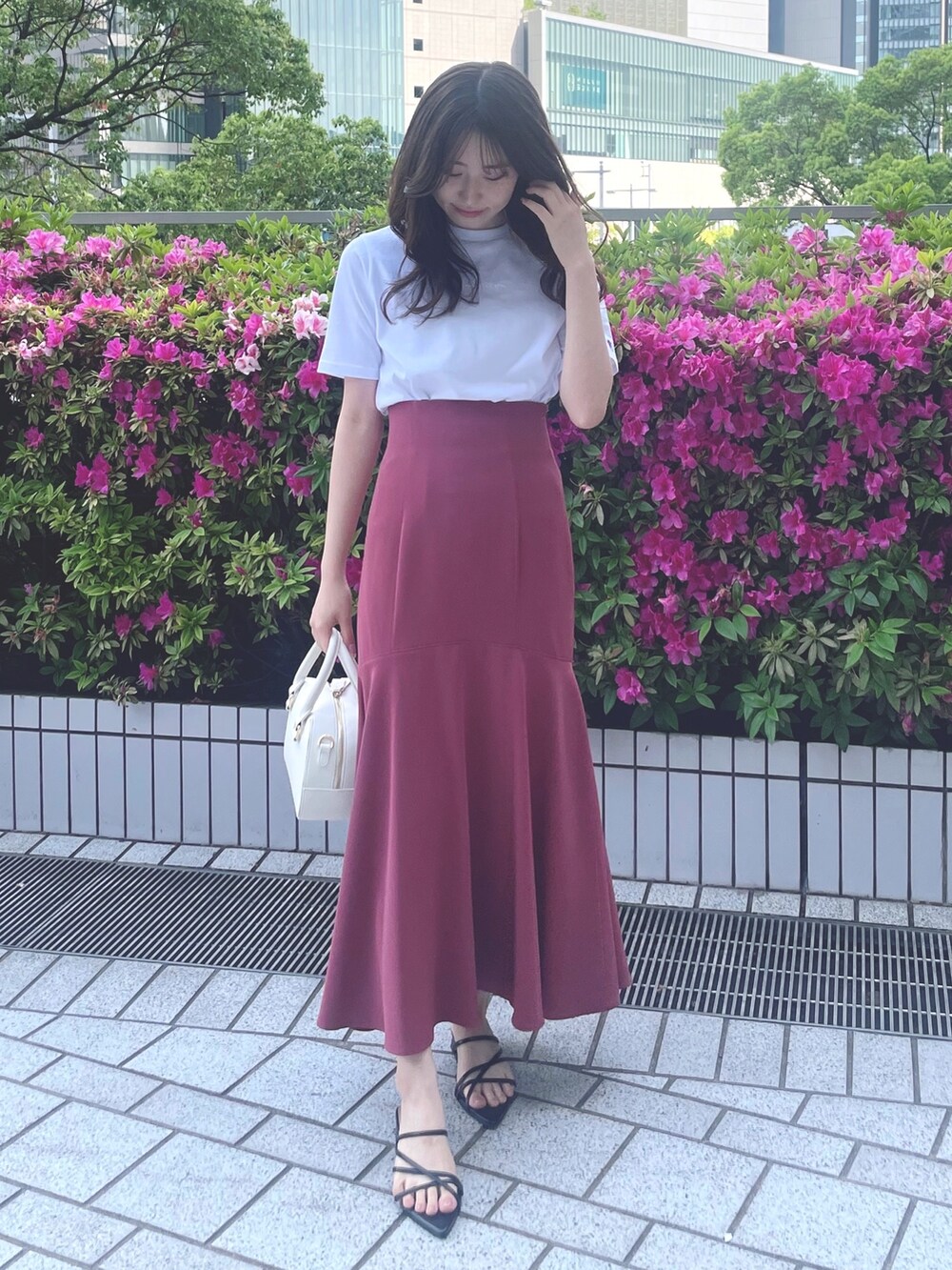 ピンク系のスカート、ホワイト系のTシャツ/カットソー、ブラック系のサンダルを着用したレディースの春コーディネートの3枚目の写真