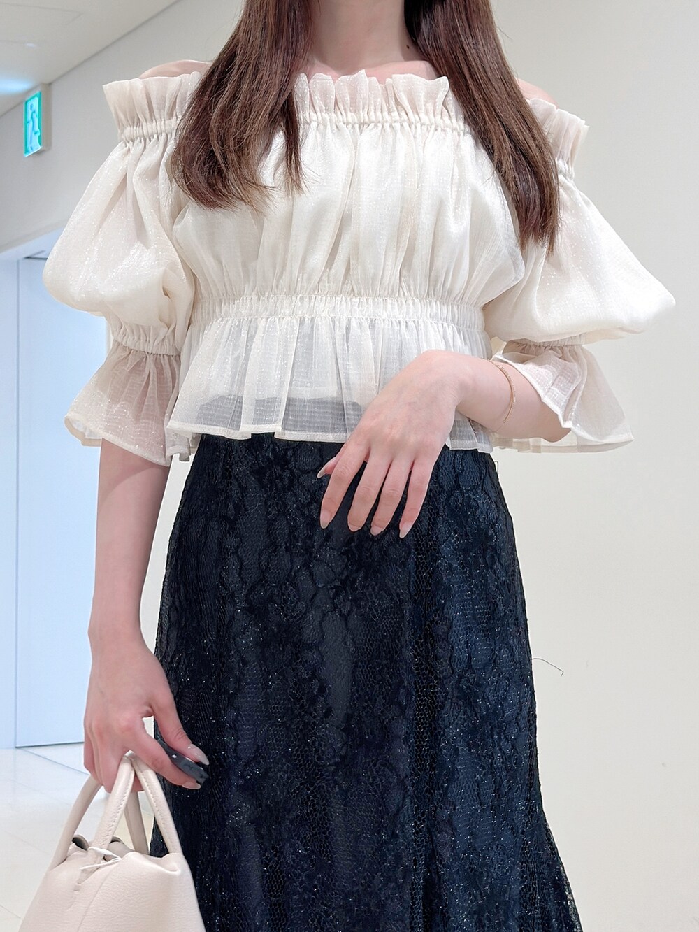 ホワイト系のシャツ/ブラウス、ブラック系のスカート、ホワイト系のサンダルを着用したレディースの春コーディネートの5枚目の写真