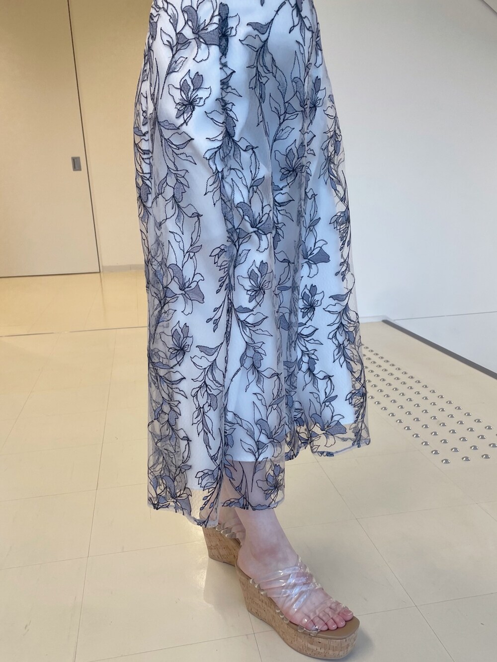 ホワイト系のニット/セーター、グレー系のスカート、その他のサンダルを着用したレディースの春コーディネートの5枚目の写真