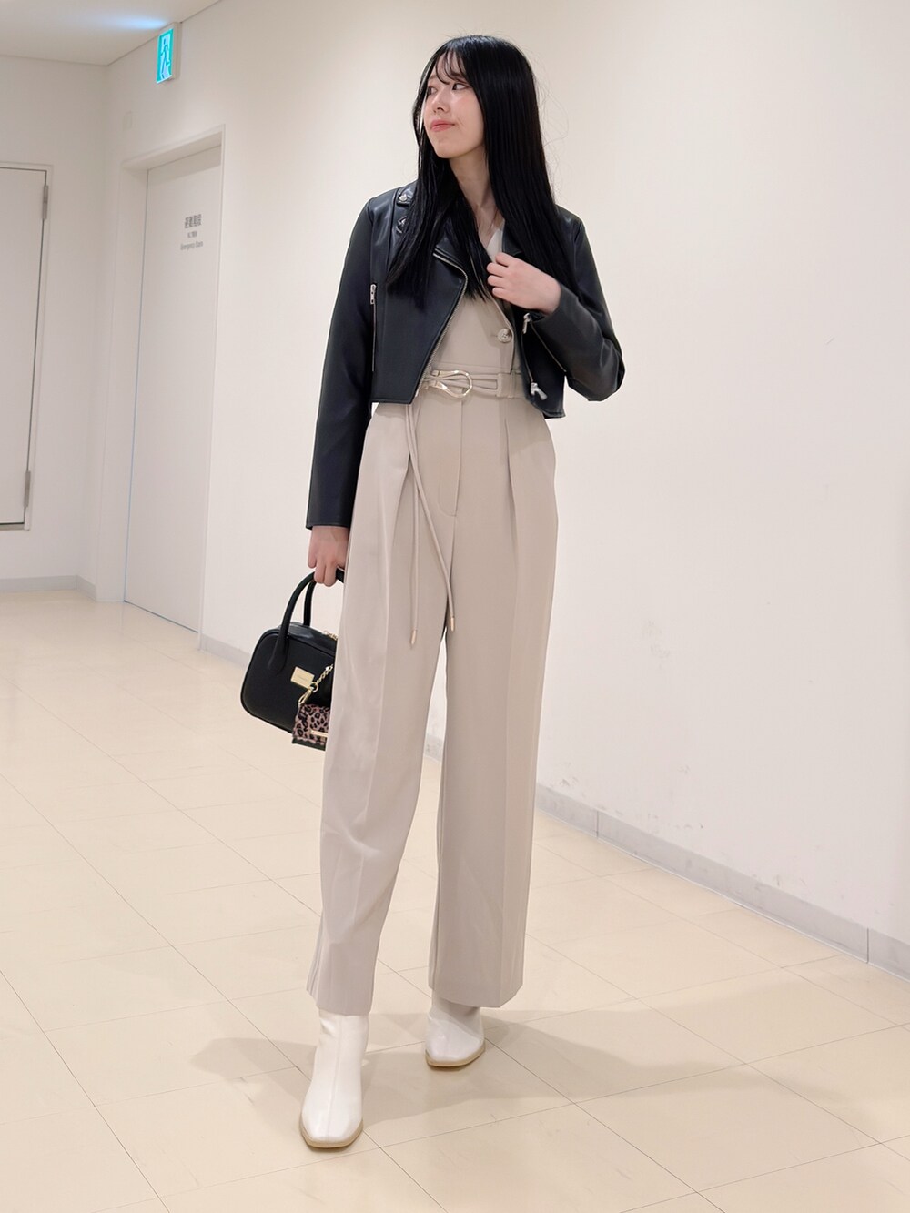 ブラック系のライダースジャケット、ベージュ系のつなぎ/オールインワン、ブラック系のハンドバッグを着用したレディースの秋コーディネートの2枚目の写真