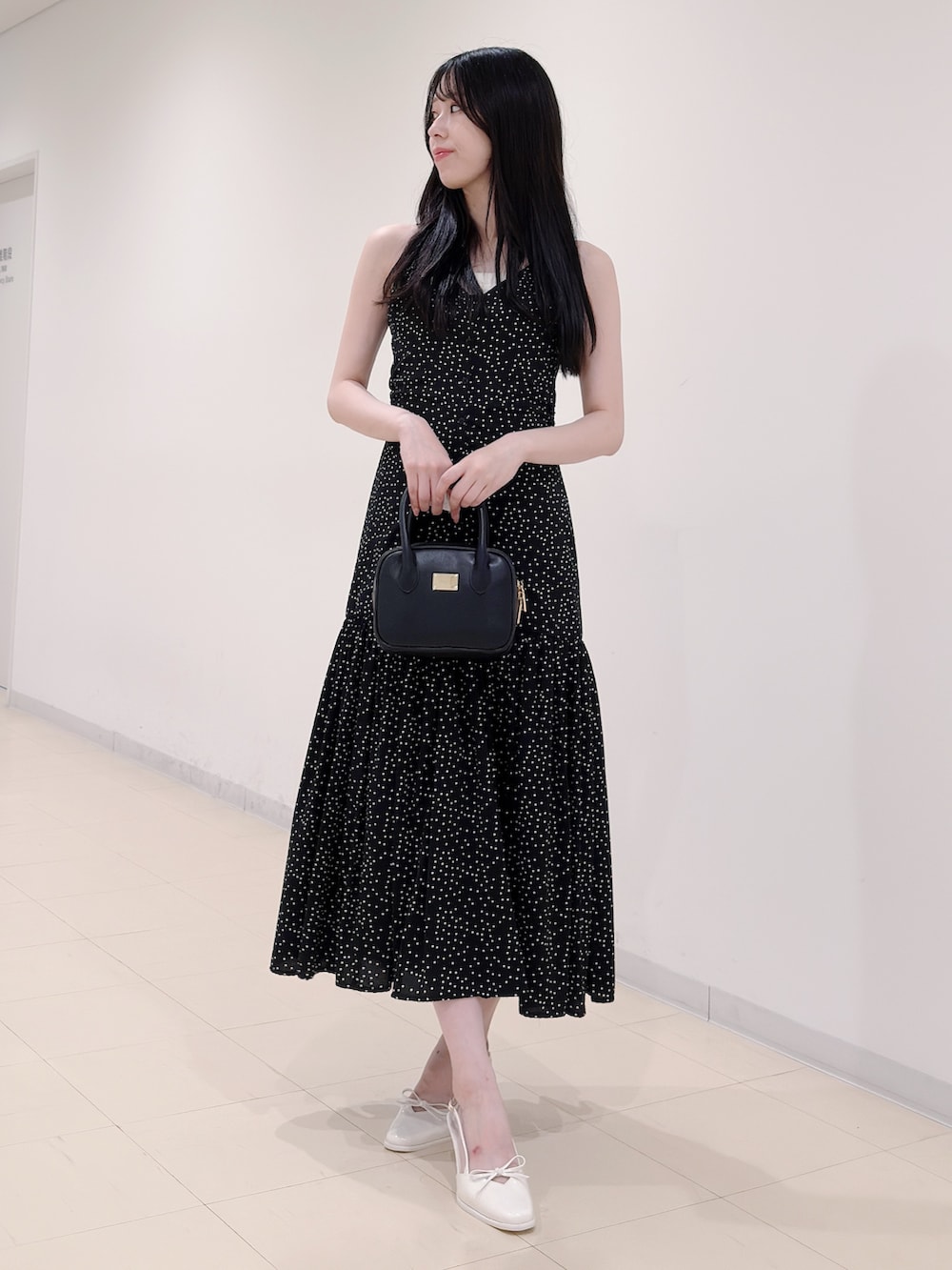 ブラック系のワンピース、ブラック系のハンドバッグ、ホワイト系のパンプスを着用したレディースの秋コーディネートの2枚目の写真