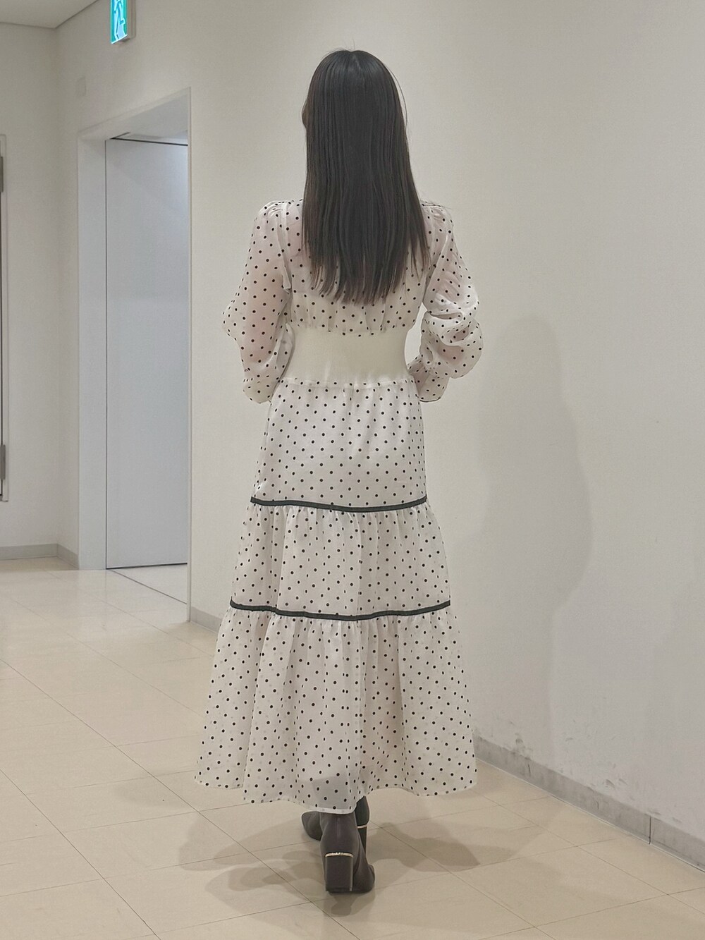 ホワイト系のワンピース、ブラウン系のハンドバッグ、ブラウン系のブーツを着用したレディースの冬コーディネートの5枚目の写真