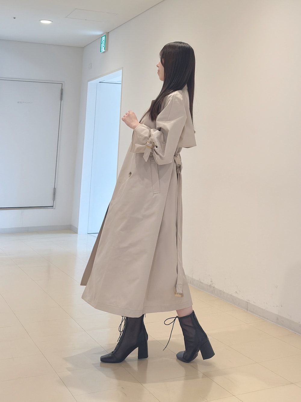 ベージュ系のトレンチコート、ホワイト系のニット/セーター、ブラック系のスカートを着用したレディースの春コーディネートの4枚目の写真