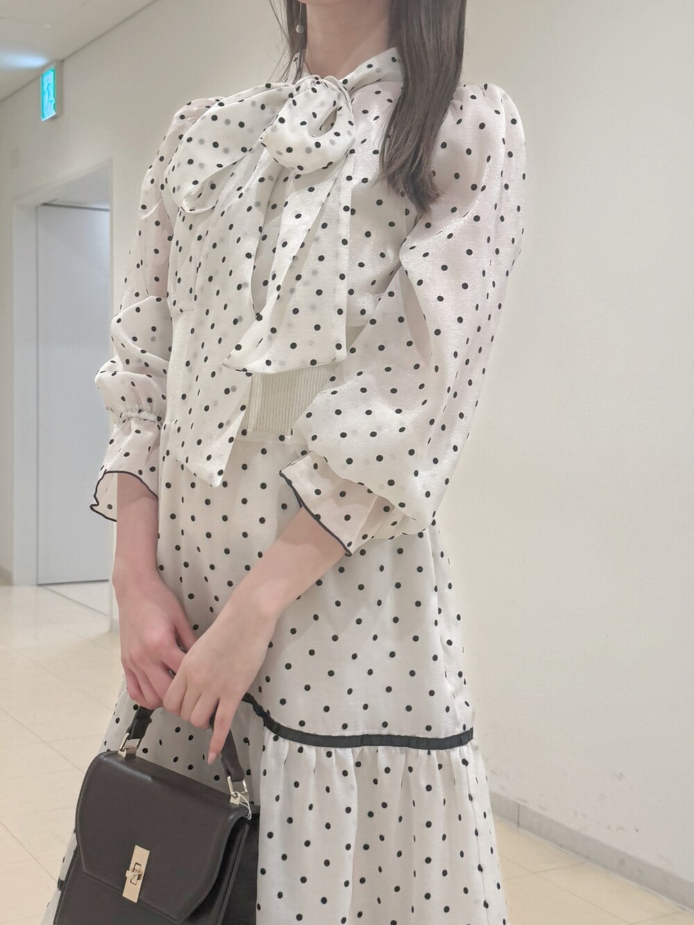 ホワイト系のワンピース、ブラウン系のハンドバッグ、ブラウン系のブーツを着用したレディースの冬コーディネートの6枚目の写真