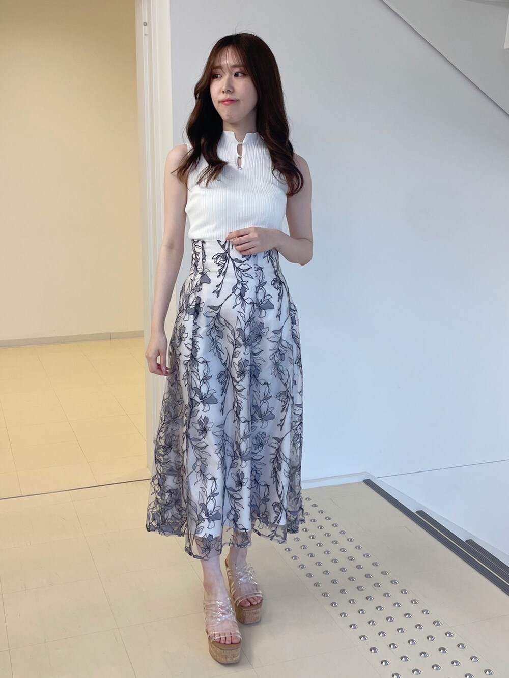 ホワイト系のニット/セーター、グレー系のスカート、その他のサンダルを着用したレディースの春コーディネートの3枚目の写真