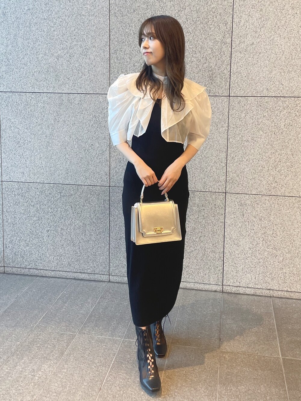 ブラック系のワンピース、シルバー系のハンドバッグ、ブラック系のブーツを着用したレディースの夏コーディネートの2枚目の写真