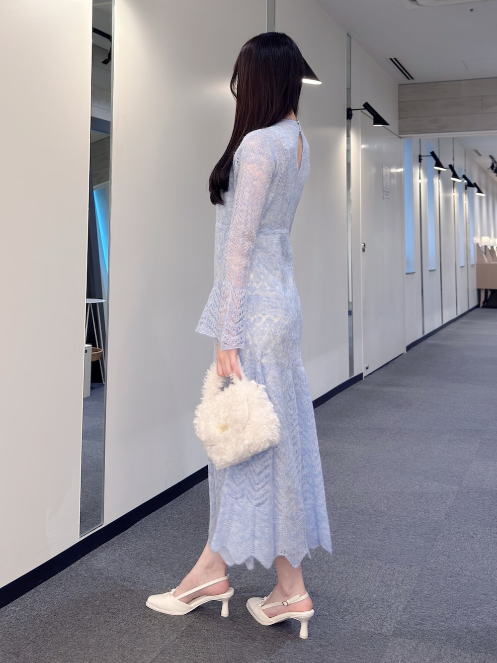 ブルー系のワンピース、ホワイト系のハンドバッグ、ホワイト系のパンプスを着用したレディースの秋コーディネートの3枚目の写真