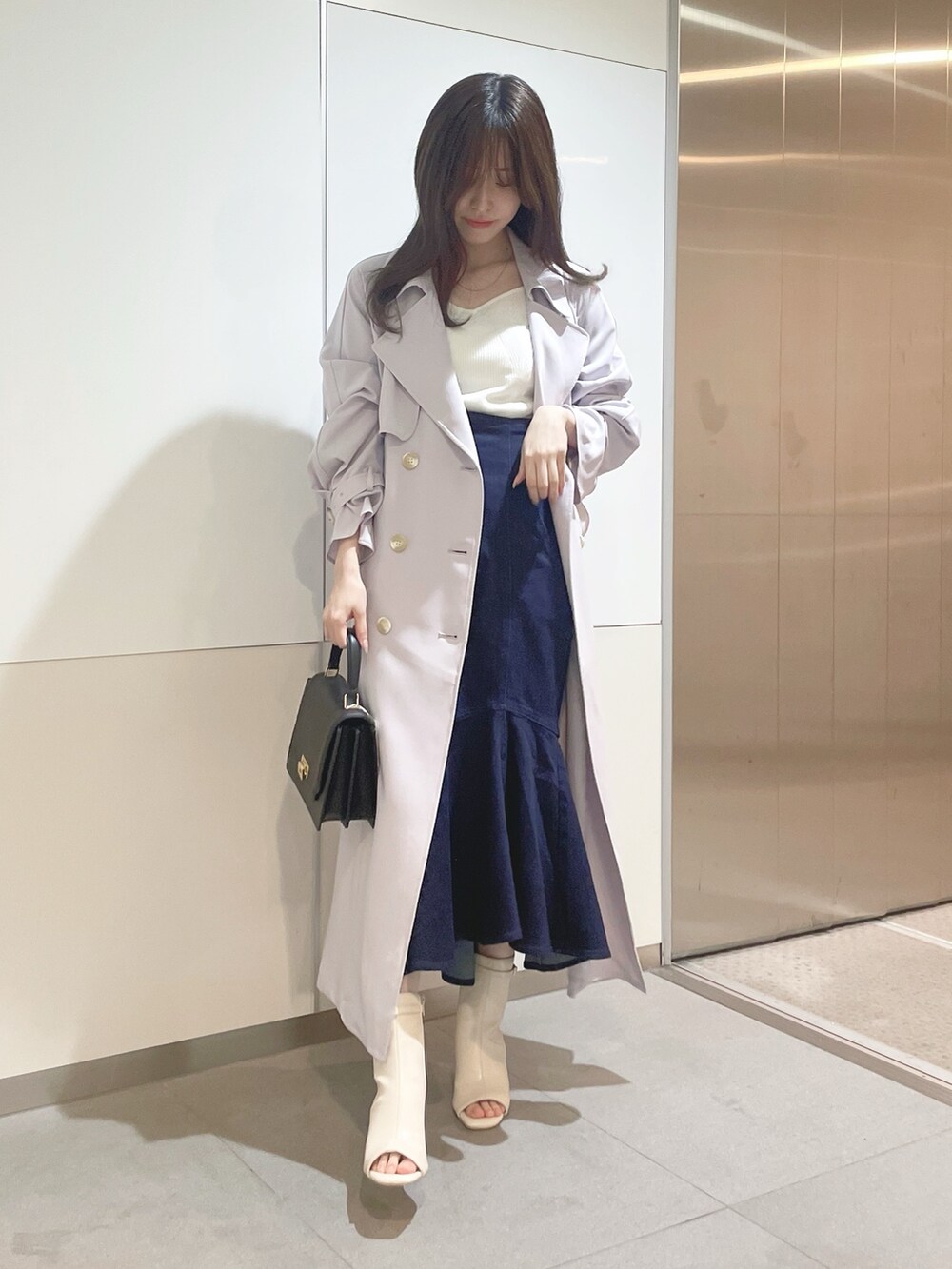 ブラック系のハンドバッグ、パープル系のトレンチコート、ホワイト系のニット/セーターを着用したレディースの冬コーディネートの2枚目の写真