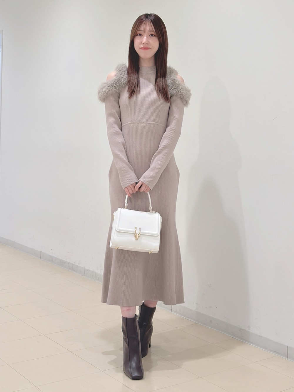 ベージュ系のワンピース、ホワイト系のハンドバッグ、ブラウン系のブーツを着用したレディースの冬コーディネートの4枚目の写真