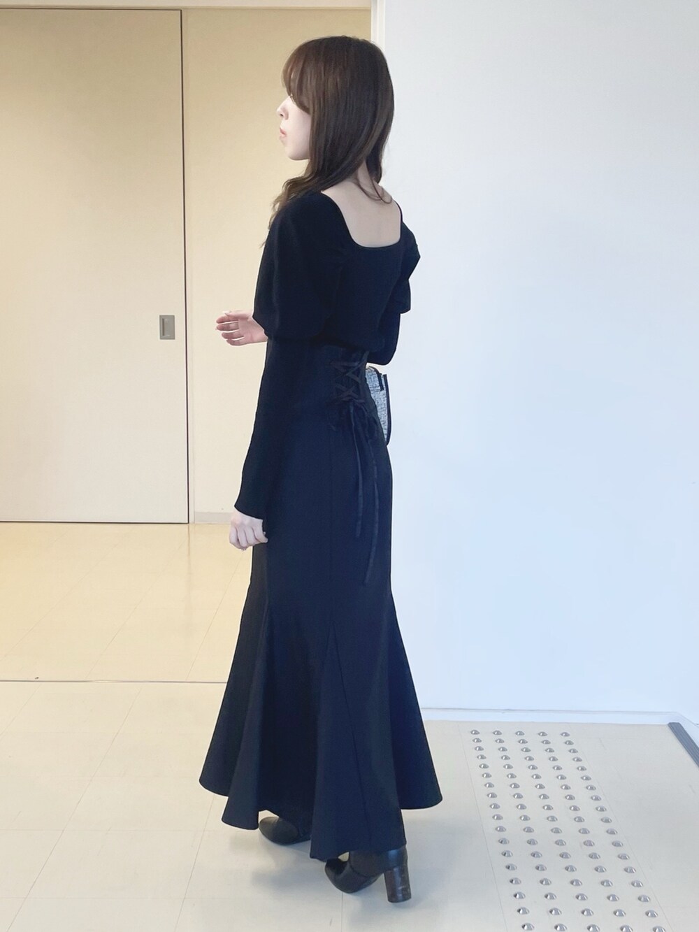 ブラック系のスカート、ブラック系のショルダーバッグ、ブラック系のブーツを着用したレディースの冬コーディネートの4枚目の写真