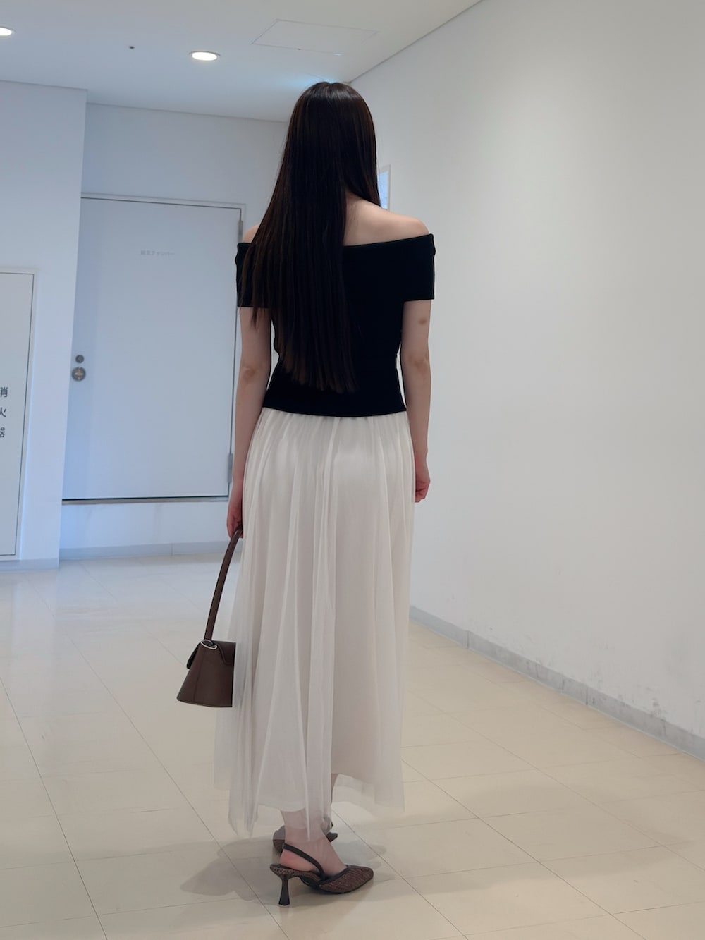 ブラック系のワンピース、ブラウン系のハンドバッグ、ブラウン系のパンプスを着用したレディースの夏コーディネートの4枚目の写真
