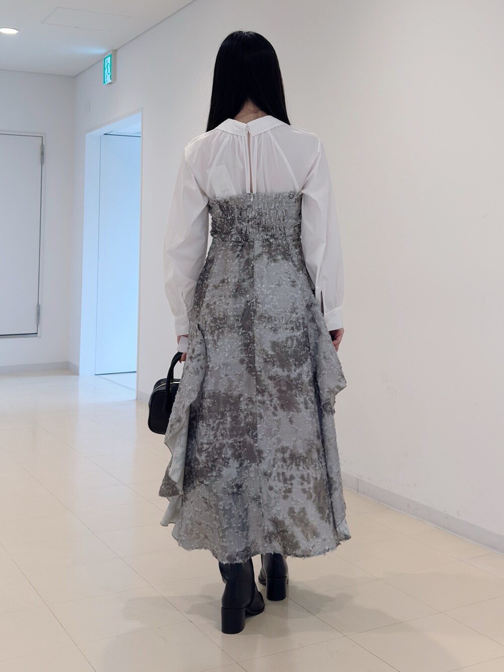 グリーン系のワンピース、ブラック系のハンドバッグ、ブラック系のブーツを着用したレディースの秋コーディネートの4枚目の写真