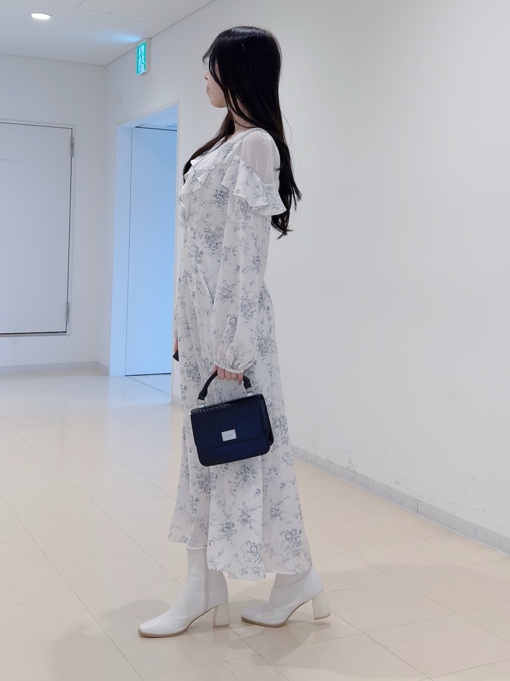 ホワイト系のワンピース、ブラック系のハンドバッグ、ホワイト系のブーツを着用したレディースの冬コーディネートの4枚目の写真