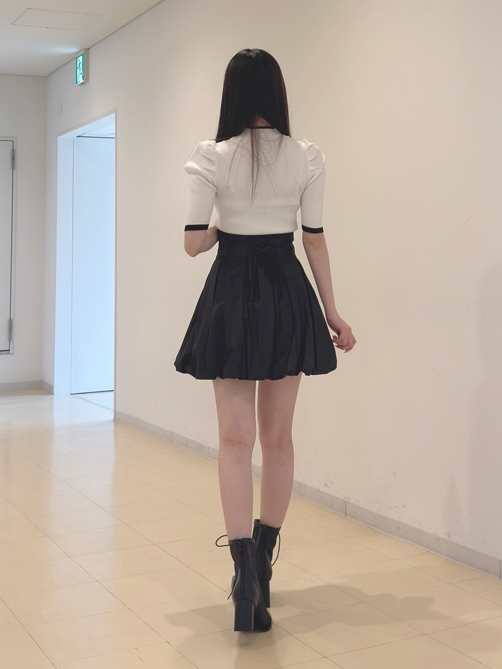 ホワイト系のニット/セーター、ブラック系のスカート、ブラック系のブーツを着用したレディースの春コーディネートの5枚目の写真