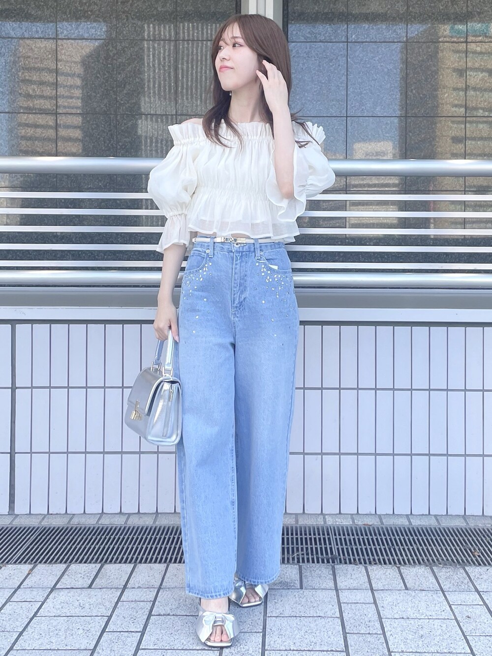 ブルー系のデニムパンツ、シルバー系のハンドバッグ、シルバー系のサンダルを着用したレディースの春コーディネートの2枚目の写真