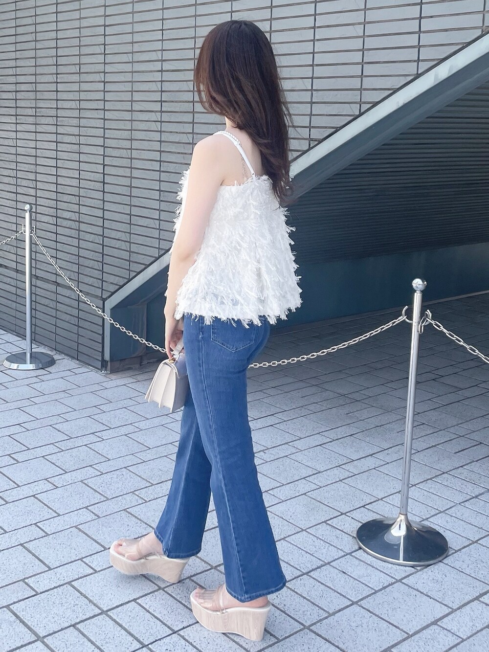 ホワイト系のキャミソール、ブルー系のデニムパンツ、その他のサンダルを着用したレディースの春コーディネートの5枚目の写真
