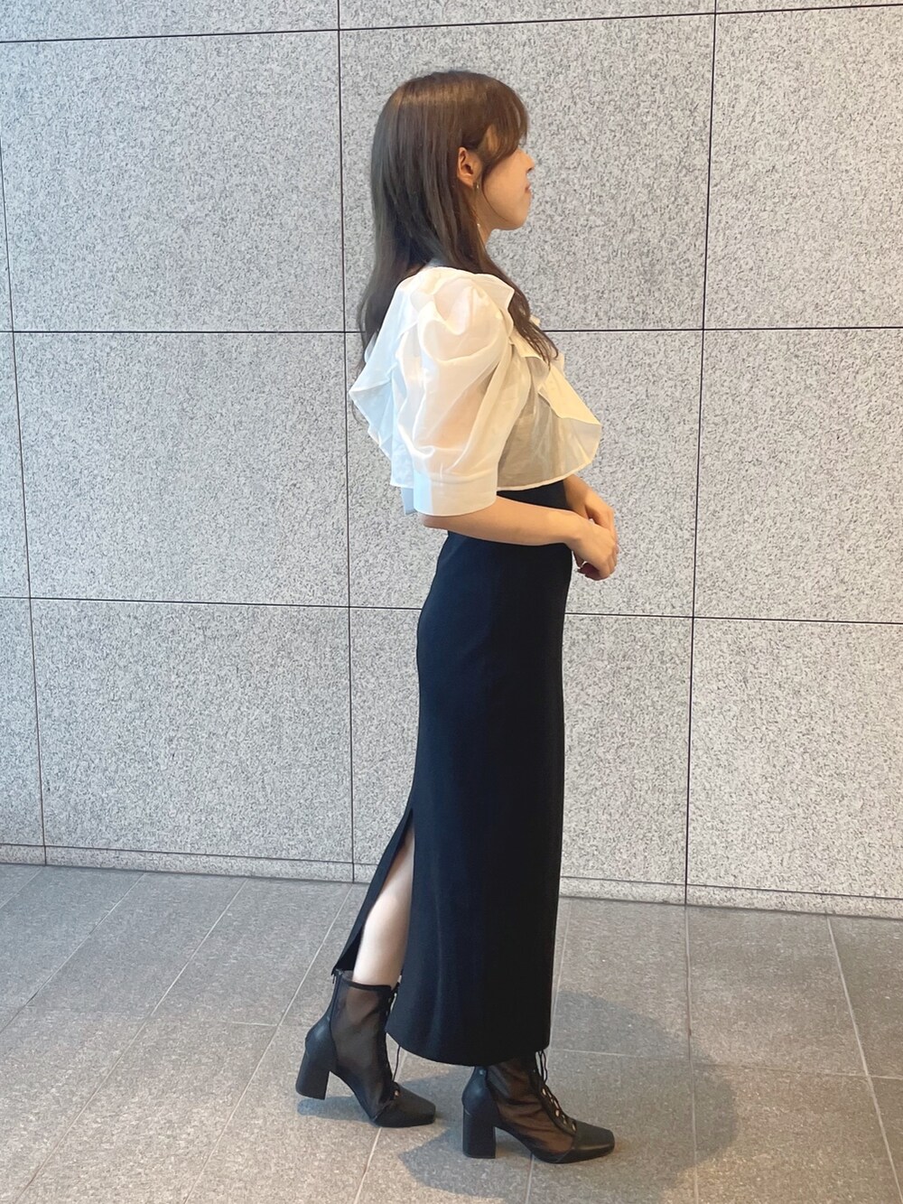 ブラック系のワンピース、シルバー系のハンドバッグ、ブラック系のブーツを着用したレディースの夏コーディネートの4枚目の写真