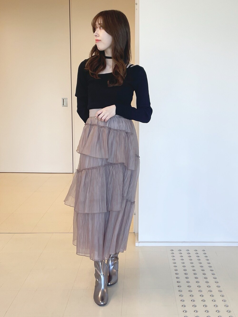 ゴールド系のブーツ、ブラウン系のスカート、ブラック系のニット/セーターを着用したレディースの冬コーディネートの2枚目の写真